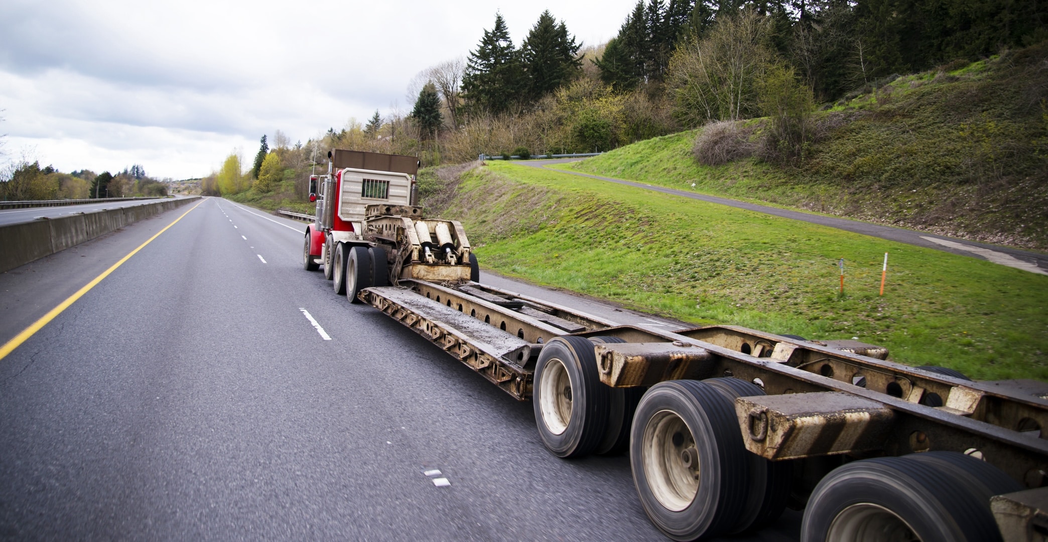 Large classic powerful big rig semi truck with a trailer for transportation of oversized and heavy cargo and objects.